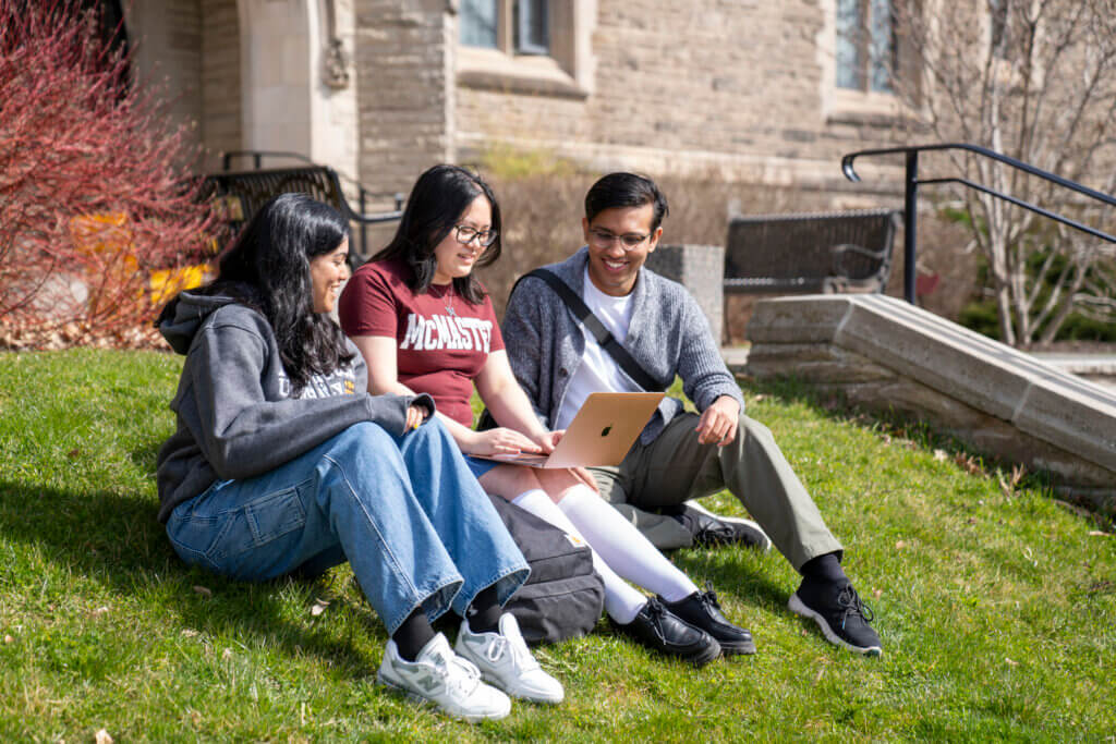 Three students sitting outside on campus.